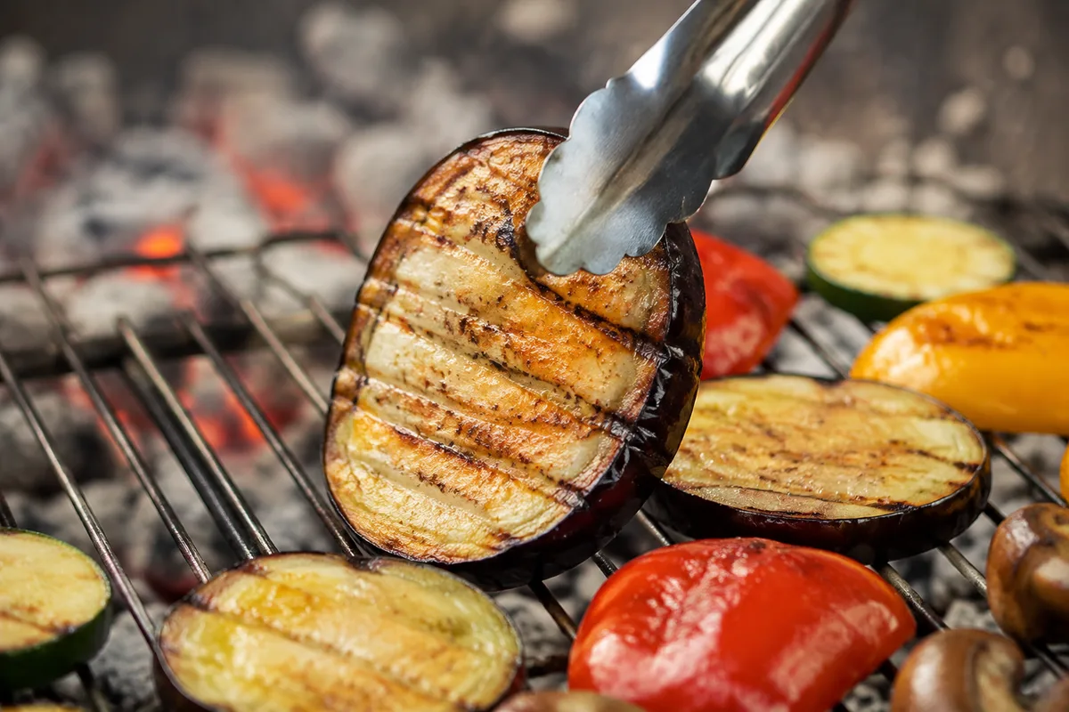 Légumes tranchés en cours de cuisson sur la grille d’un barbecue